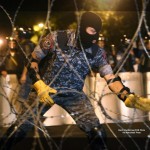 A riot police officer installs barbed wire as others block the street towards the Presidential Residence to prevent a march of anti-government protesters, supporters of the armed group who have been holed inside a police station, in Yerevan, Armenia, Saturday, July 30, 2016. Armed members of an opposition group barricaded inside a police station in Armenia's capital shot an officer dead on Saturday, police said. (Hrant Khachatryan/PAN Photo via AP)